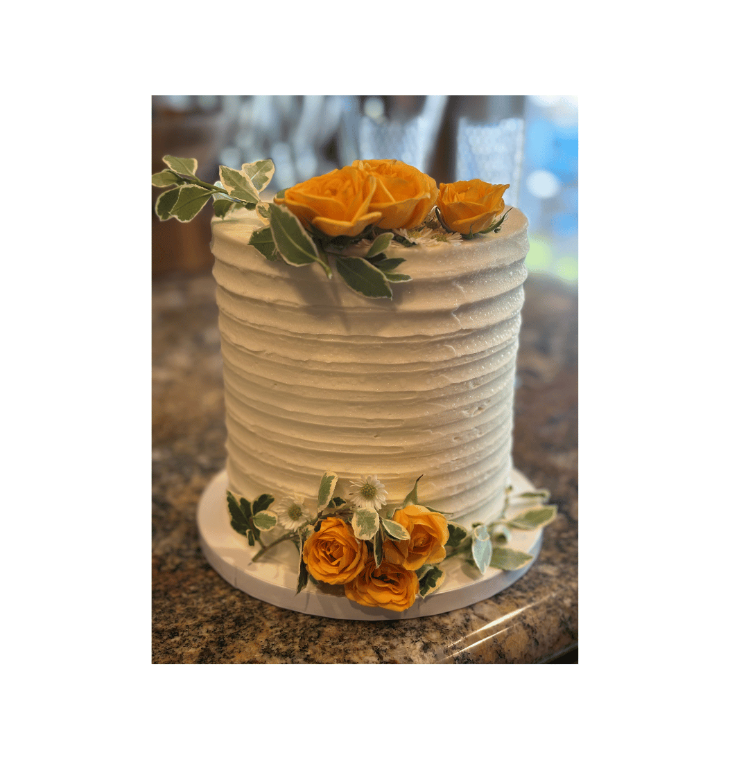 Rustic white layered cake with fresh golden roses and greenery